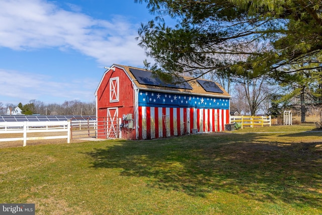 view of barn with a yard and fence