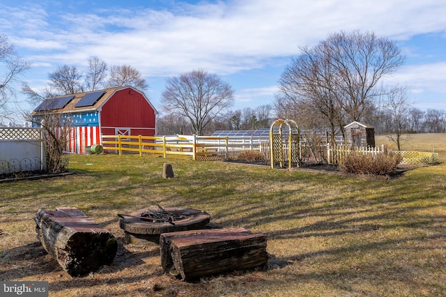 view of yard with a barn, an outdoor structure, and fence