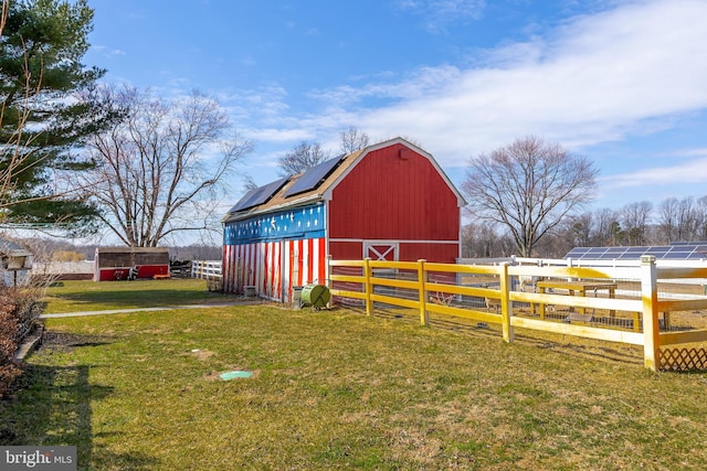 view of barn with a lawn and fence