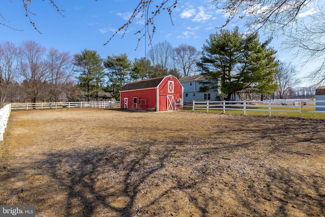 view of yard featuring an enclosed area, a barn, an outdoor structure, and fence