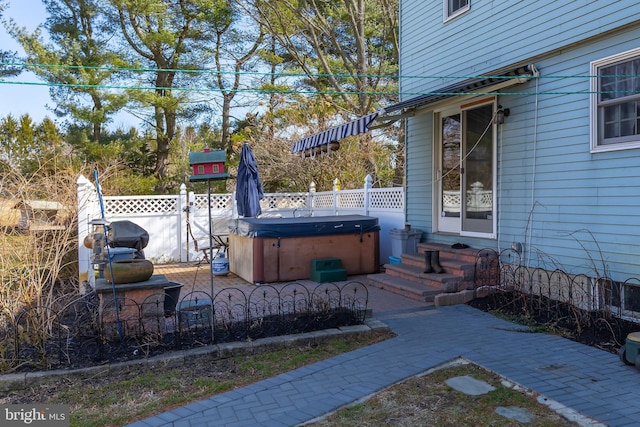 view of patio / terrace with fence, entry steps, and a hot tub