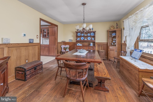 dining room with a notable chandelier, hardwood / wood-style floors, and wainscoting