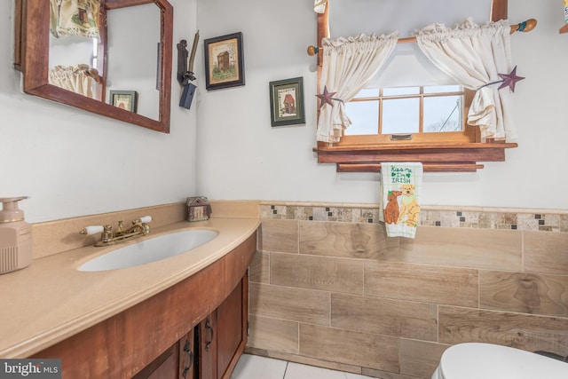 half bathroom with toilet, tile walls, vanity, and tile patterned flooring