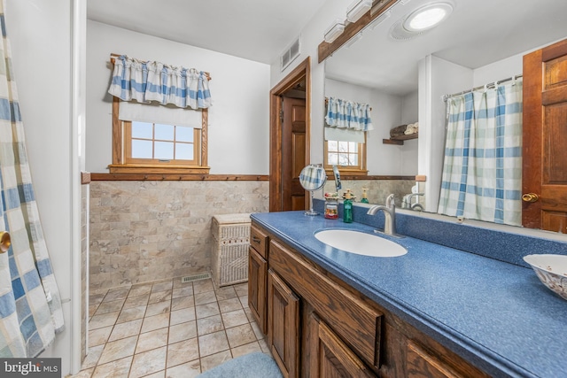 full bathroom featuring visible vents, tile walls, a wainscoted wall, and vanity