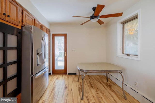 kitchen with ceiling fan, a baseboard radiator, stainless steel fridge with ice dispenser, light wood finished floors, and brown cabinetry