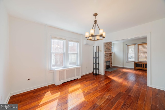 unfurnished dining area with a healthy amount of sunlight, a wall unit AC, wood-type flooring, and radiator heating unit