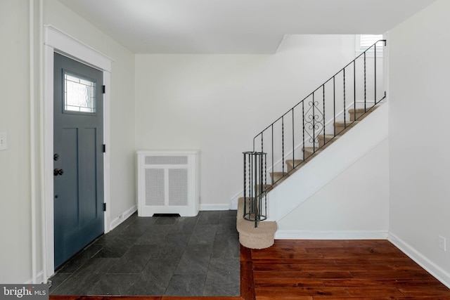 entryway with dark wood-type flooring, baseboards, and stairs