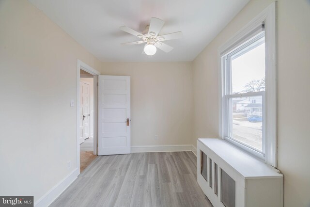 interior space featuring light wood-type flooring, a ceiling fan, and baseboards