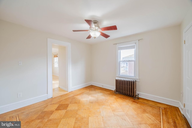 spare room featuring baseboards, ceiling fan, and radiator