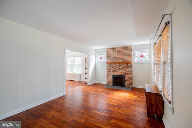 unfurnished living room with radiator, wood-type flooring, a fireplace, and baseboards