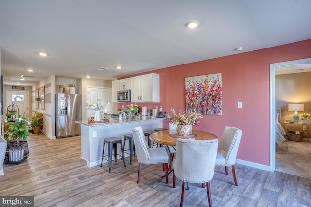 dining room featuring light wood finished floors, visible vents, baseboards, and recessed lighting