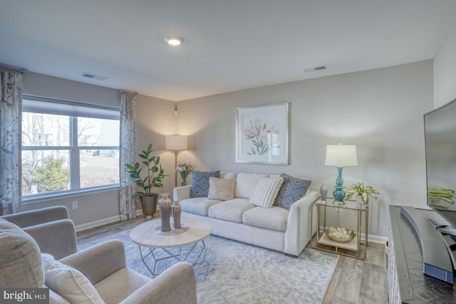 living area with baseboards, visible vents, and wood finished floors