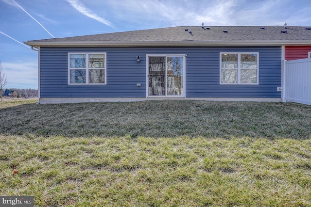 back of property featuring a shingled roof and a lawn