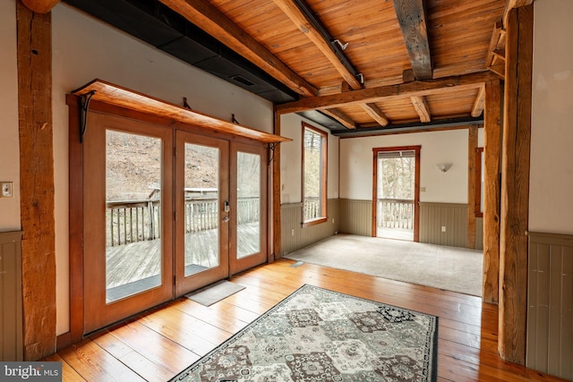 doorway featuring french doors, a wainscoted wall, wood-type flooring, wood ceiling, and beamed ceiling