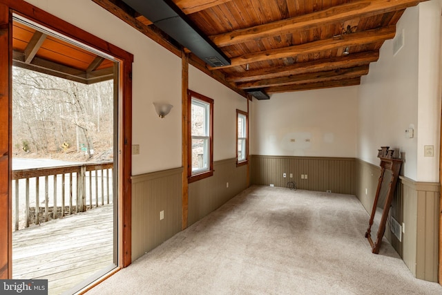 carpeted spare room with wooden ceiling, wainscoting, and beam ceiling