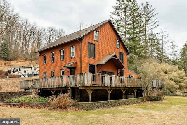 rear view of house with a lawn and a wooden deck