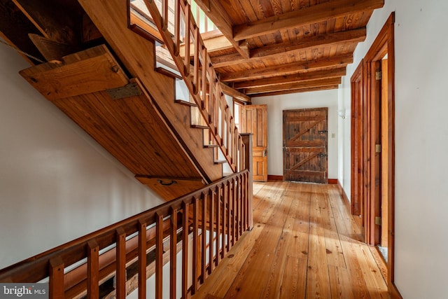 hallway with stairs, beam ceiling, wooden ceiling, and light wood-style flooring