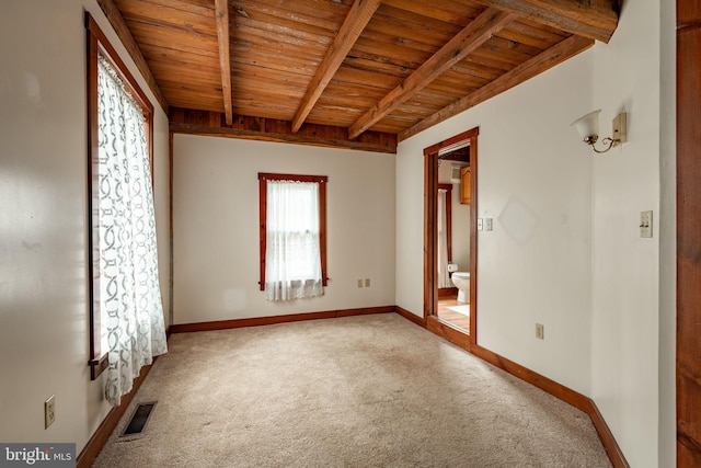 carpeted empty room featuring wooden ceiling, baseboards, visible vents, and beam ceiling