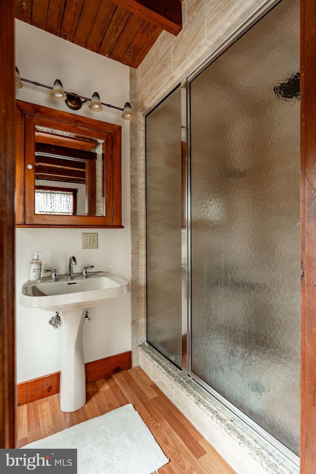 full bathroom featuring wooden ceiling, a sink, wood finished floors, a stall shower, and beamed ceiling