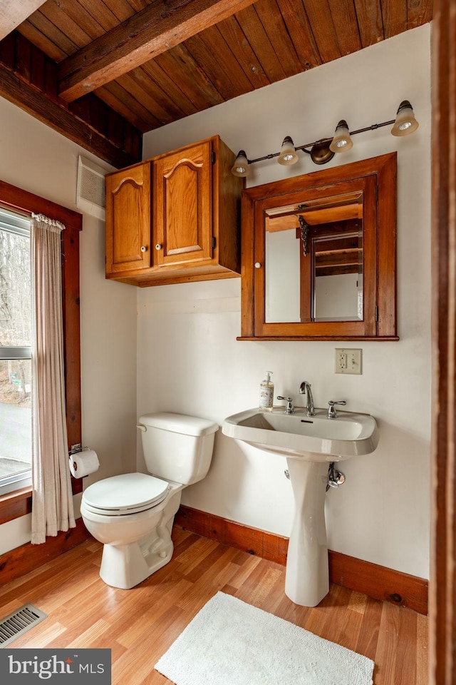 half bath featuring baseboards, visible vents, toilet, wooden ceiling, and wood finished floors