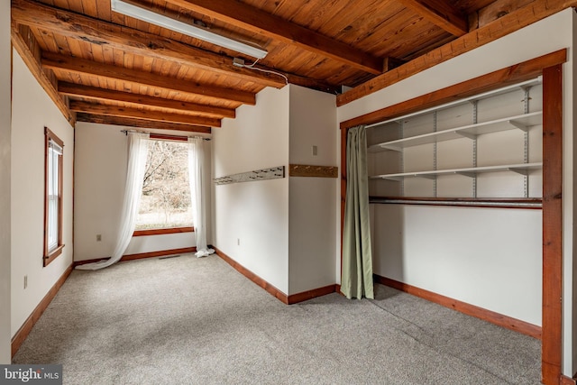 unfurnished bedroom with carpet floors, a closet, wooden ceiling, beamed ceiling, and baseboards