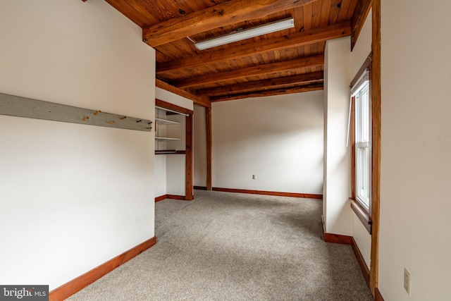 spare room featuring wood ceiling, carpet flooring, beam ceiling, and baseboards