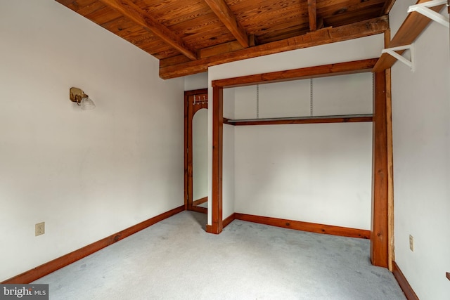 unfurnished bedroom featuring beamed ceiling, carpet, wood ceiling, and baseboards