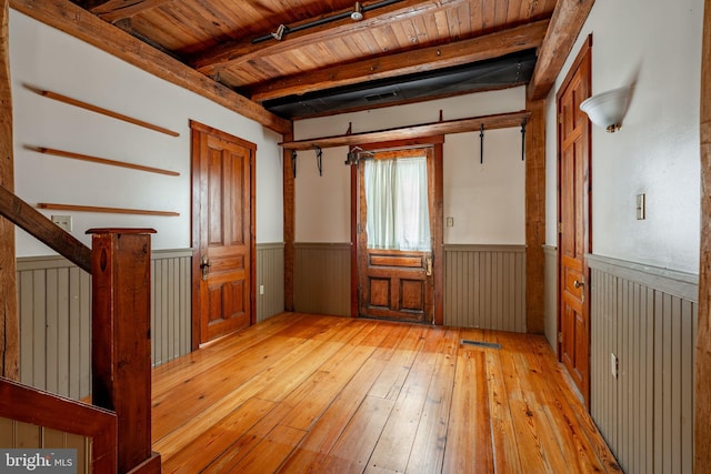 unfurnished room with beamed ceiling, wainscoting, wooden ceiling, and light wood-style floors