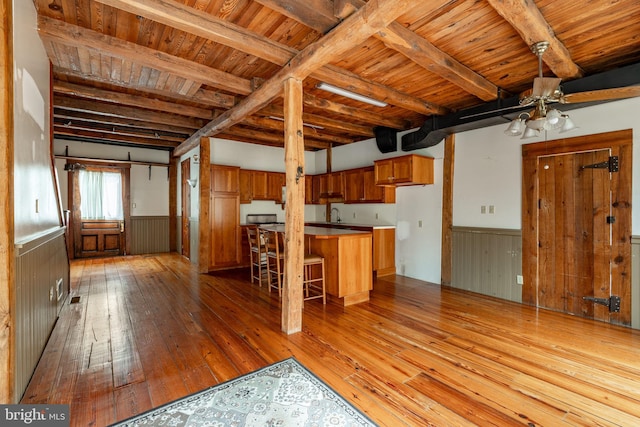 kitchen with brown cabinets, wood ceiling, a wainscoted wall, and beam ceiling