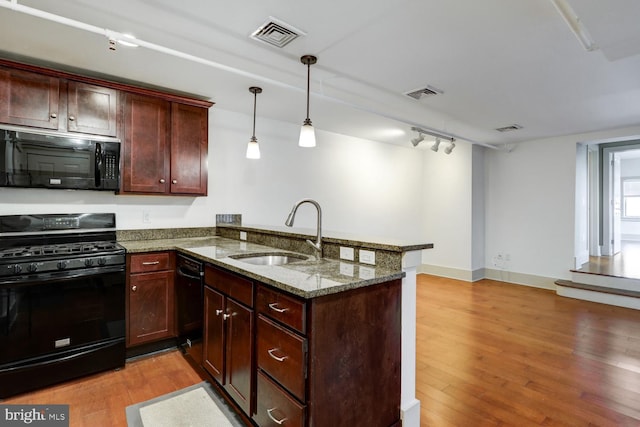 kitchen featuring a peninsula, a sink, visible vents, light wood-style floors, and black appliances