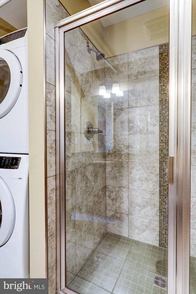 bathroom with a shower stall and stacked washer / drying machine