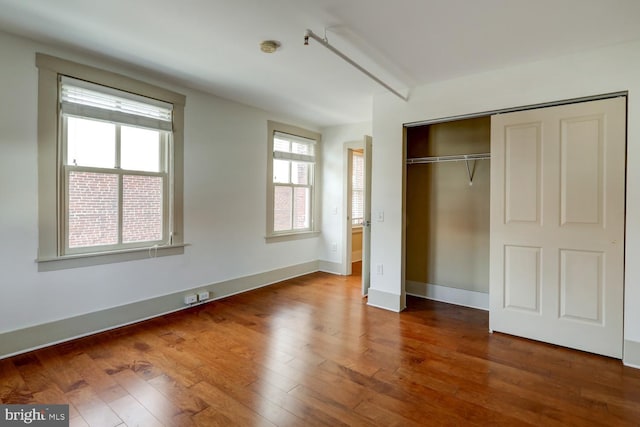 unfurnished bedroom with hardwood / wood-style flooring, baseboards, and a closet