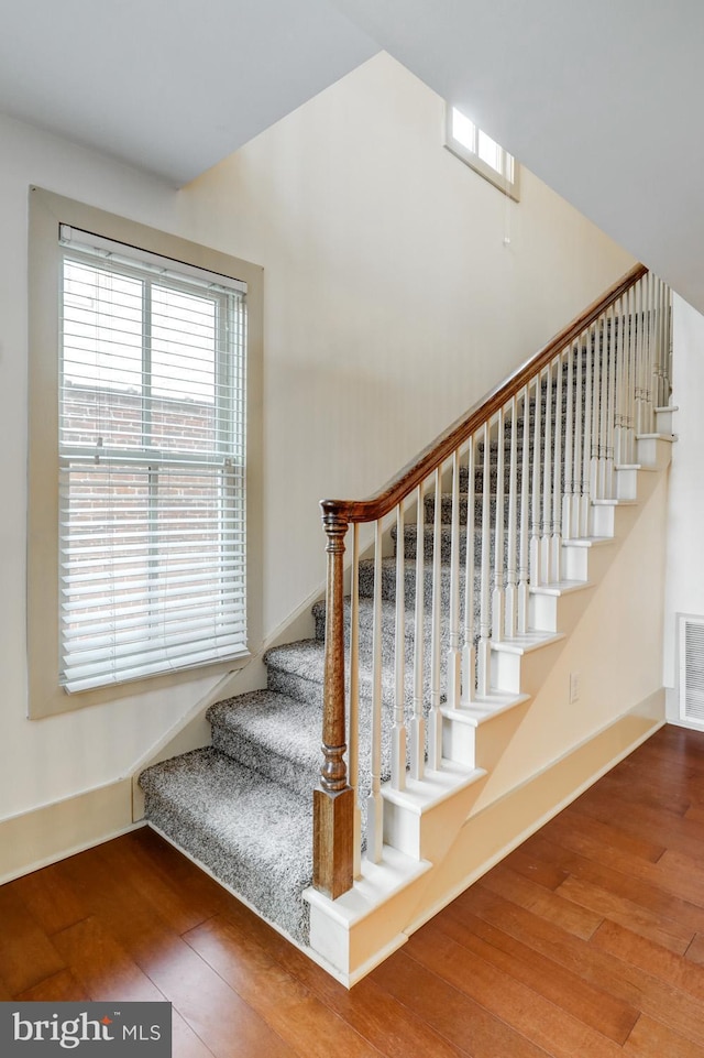 staircase with visible vents, baseboards, and hardwood / wood-style floors