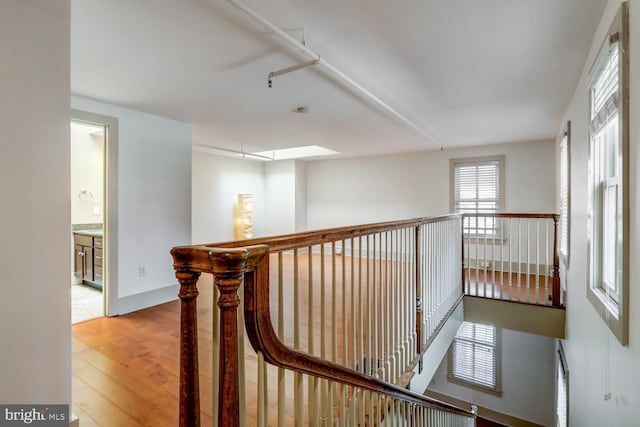 hall with an upstairs landing, a skylight, baseboards, and wood finished floors