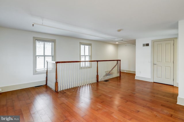 spare room featuring attic access, baseboards, visible vents, and light wood finished floors