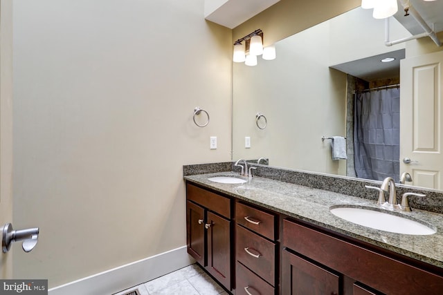 full bathroom featuring double vanity, tile patterned flooring, baseboards, and a sink