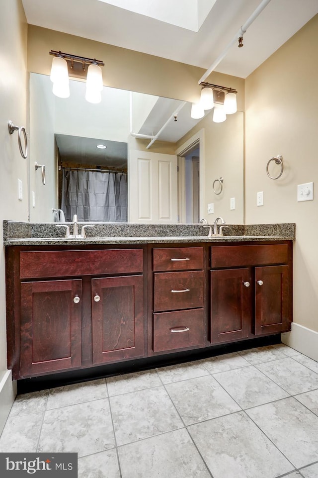 bathroom featuring double vanity, baseboards, and tile patterned floors