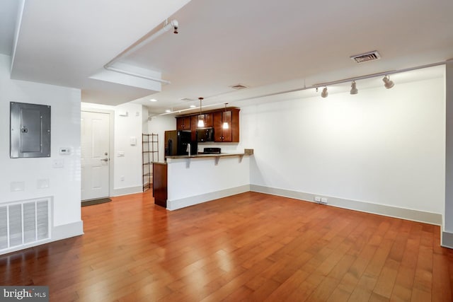 unfurnished living room with baseboards, electric panel, visible vents, and hardwood / wood-style floors