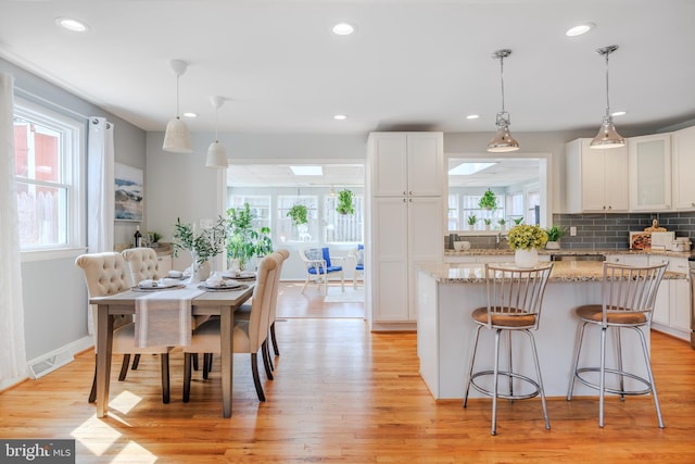 kitchen featuring light wood finished floors, white cabinetry, visible vents, and a center island