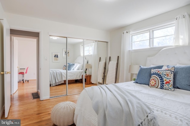 bedroom with baseboards, a closet, visible vents, and light wood-style floors