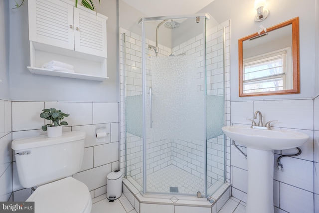 bathroom featuring toilet, a shower stall, and tile walls