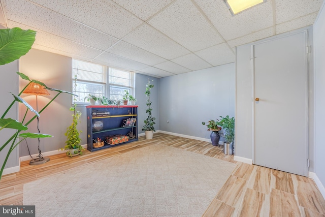 sitting room with a paneled ceiling, baseboards, and wood finished floors