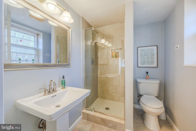 bathroom with a stall shower, baseboards, toilet, tile patterned flooring, and a sink