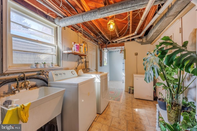 washroom with laundry area, a sink, and washing machine and clothes dryer