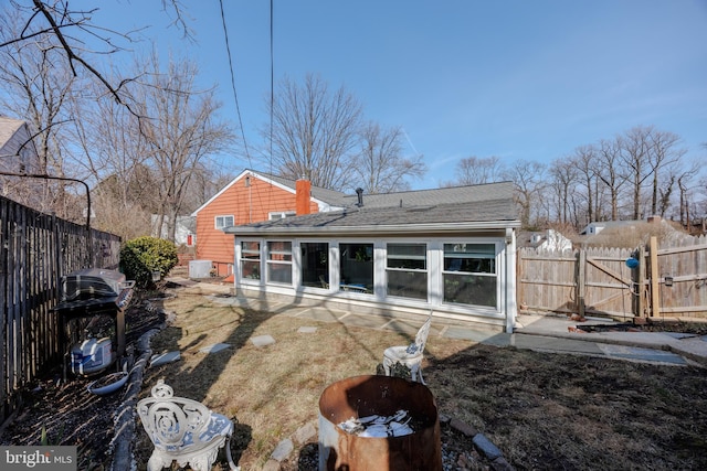 back of property featuring a shingled roof, a gate, and fence