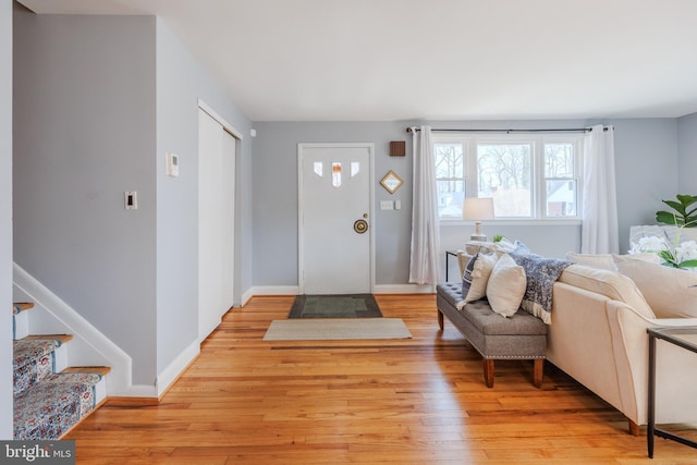 foyer entrance with light wood-style flooring, stairs, and baseboards