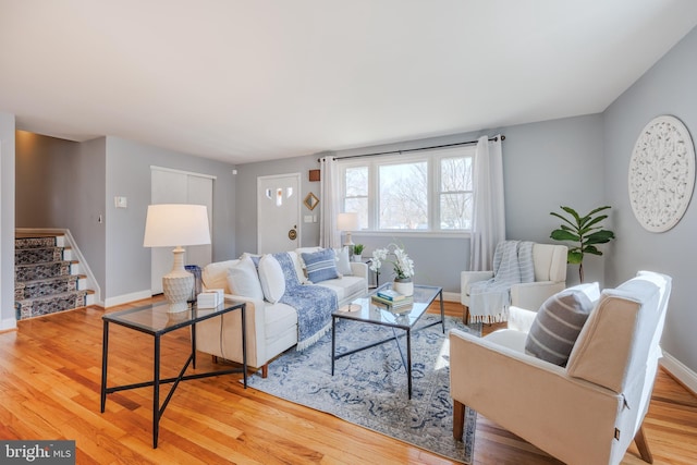 living room featuring stairway, baseboards, and wood finished floors