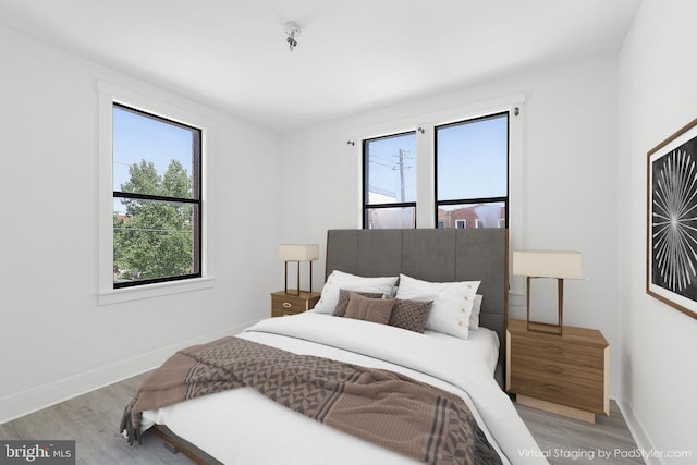 bedroom featuring multiple windows, light wood-type flooring, and baseboards