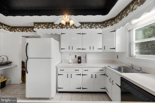 kitchen featuring black dishwasher, a sink, freestanding refrigerator, and white cabinets