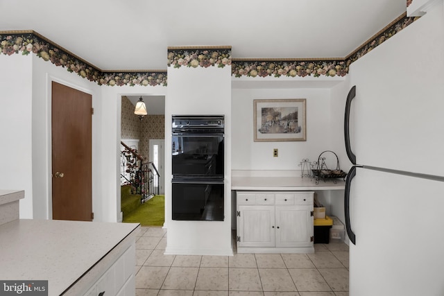 kitchen featuring light countertops, white cabinetry, freestanding refrigerator, and dobule oven black